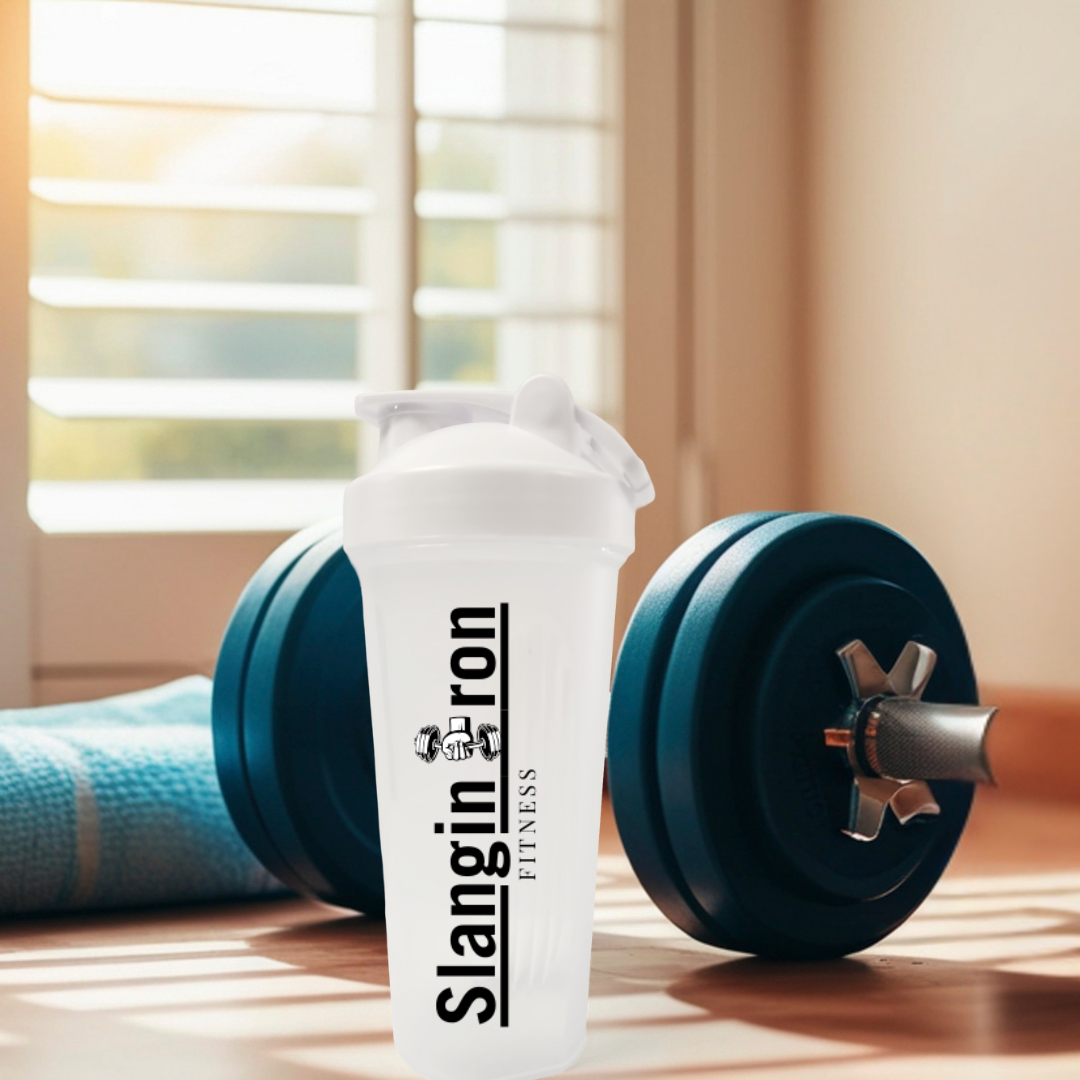 Shaker bottle with 'Slangin Iron Fitness' branding next to a blue dumbbell on a wooden surface.