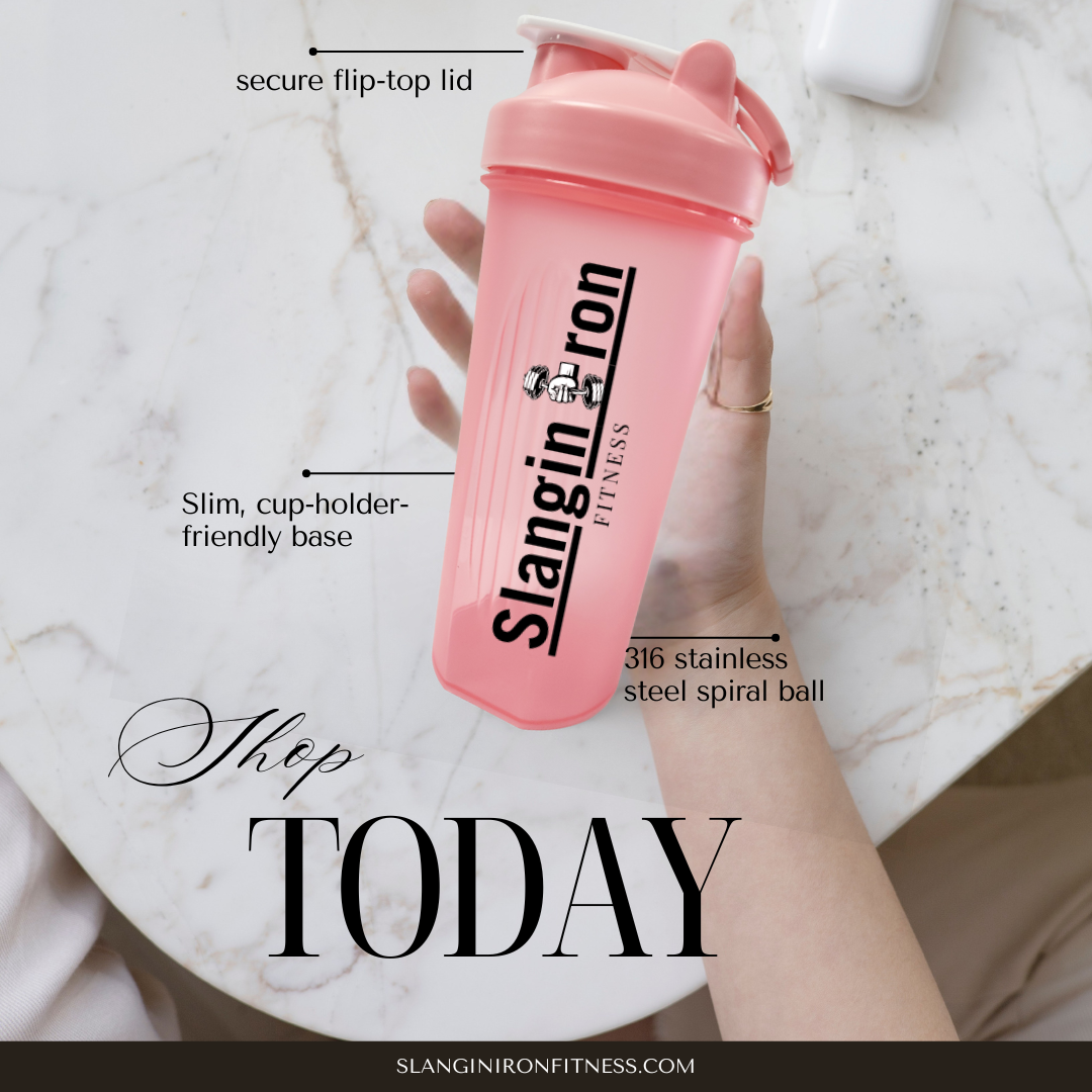Pink Shaker bottle with 'Slangin Iron Fitness' branding held by a hand on a marble surface.
