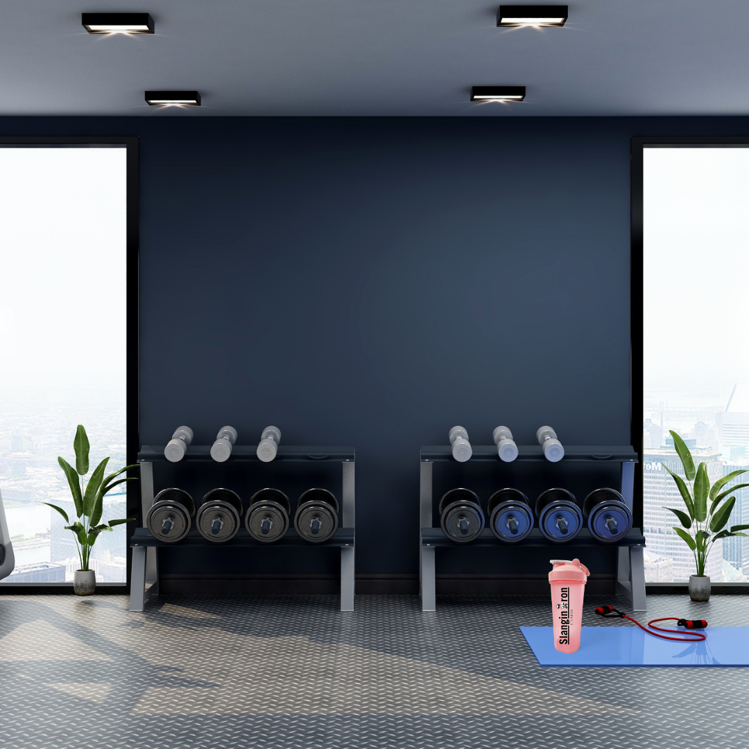 Gym interior with dumbbells on racks, a pink shaker bottle, and a blue mat.